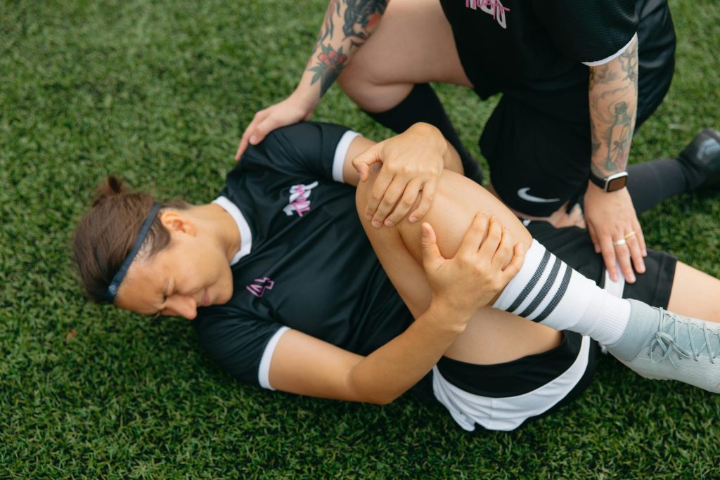 Jugadora de fútbol en el suelo abrazándose la rodilla
